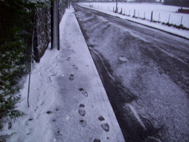 Snow takes over cleared and gritted footpath and road, the boots bite through